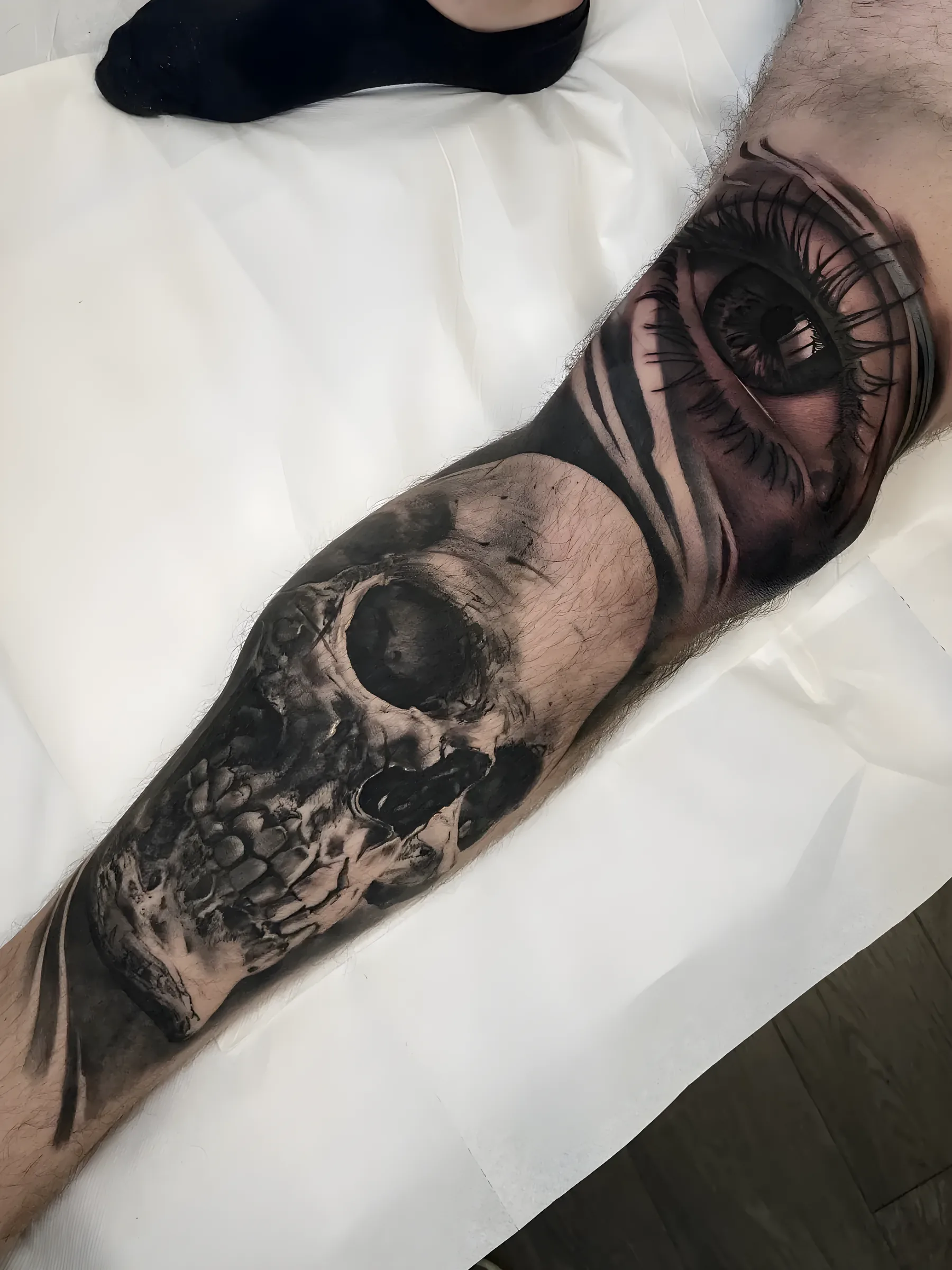 Black and grey skull and eye on the forearm