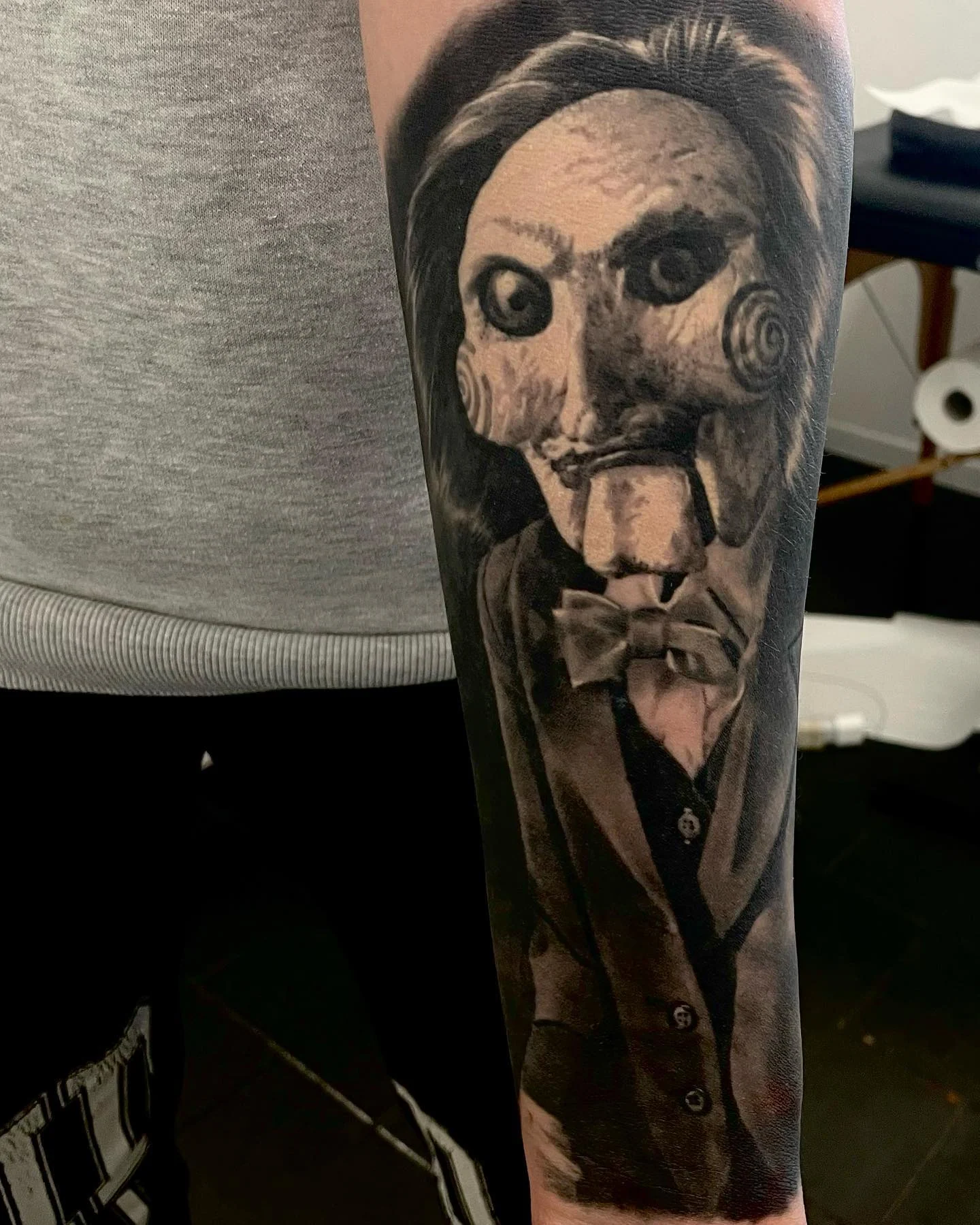 Black and grey Billy the Puppet portrait on the upper arm