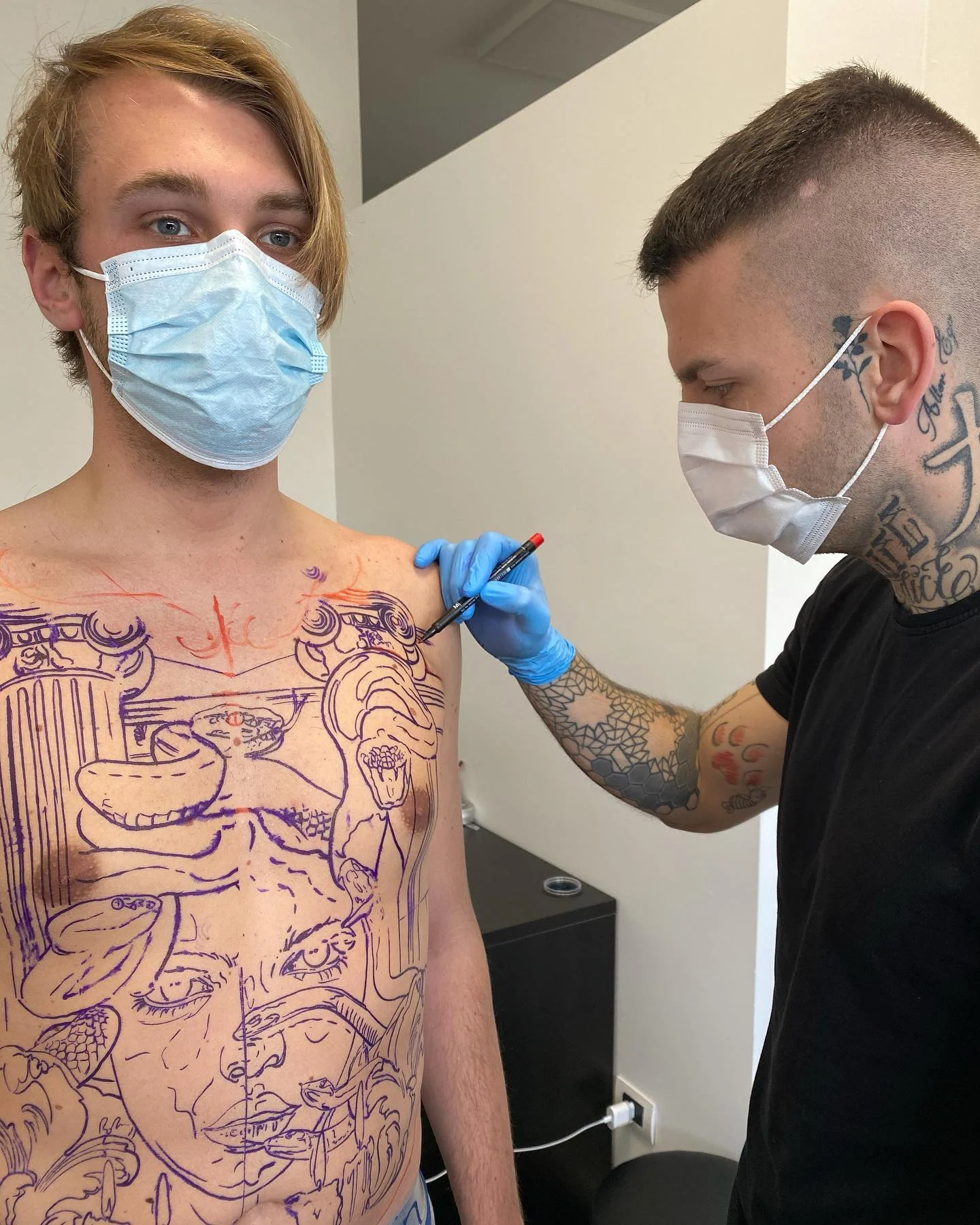 Federico drawing a full torso design freehand on the skin in marker, before any tattooing