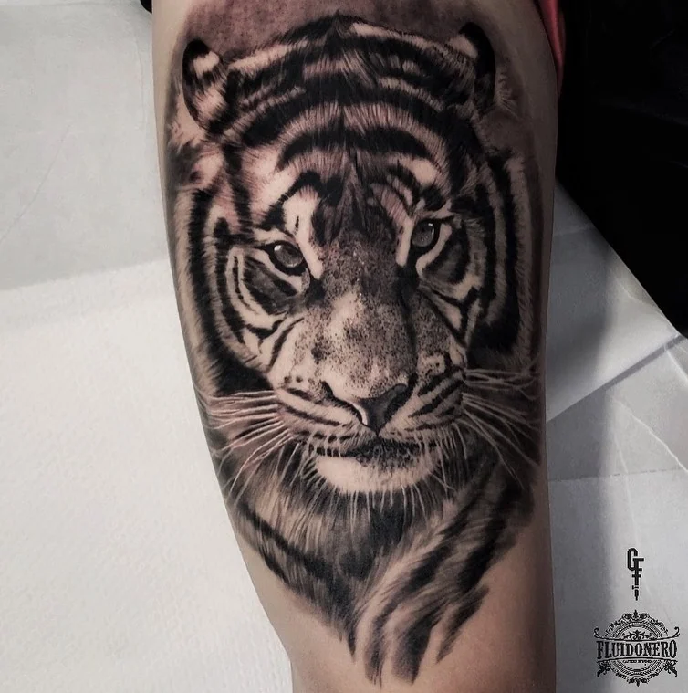 Black and grey realistic tiger head on the thigh