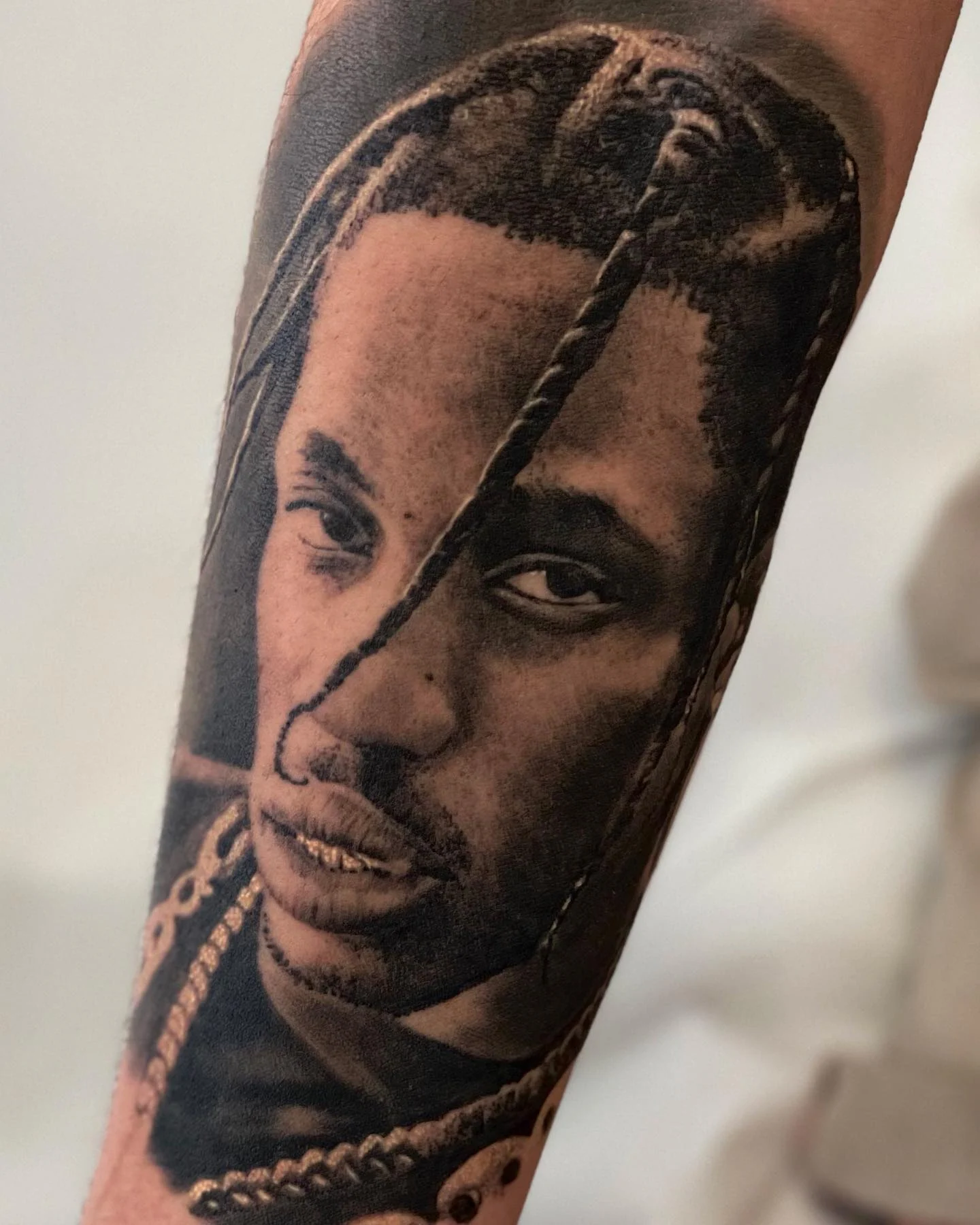 Black and grey portrait of Travis Scott on the forearm
